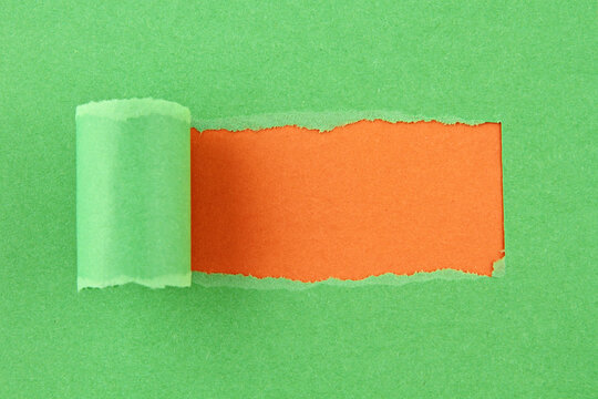 Torn green paper rolled back revealing bright orange layer underneath creating bold abstract background with copy space for advertising, branding, and creative message design
