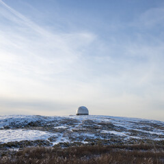 The white dome (radiotransparent shelter) of an abandoned radar station on the top of a mountain. Tourist attraction in the vicinity of Magadan. Magadan region, Far East of Russia.