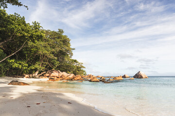 A tranquil tropical beach scene featuring clear shallow water and soft white sand