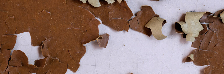Peeling paint on the wall. Panorama of a concrete wall with old cracked flaking paint. Weathered rough painted surface with patterns of cracks and peeling. Wide panoramic grunge texture for background