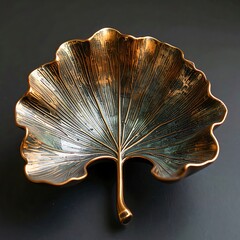 Ornate leaf-shaped metal bowl with etched details and tarnished copper/bronze finish on a dark surface