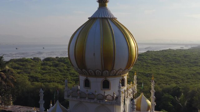 Aerial drone push back revealing coastal domed mausoleum architecture in Mumbai