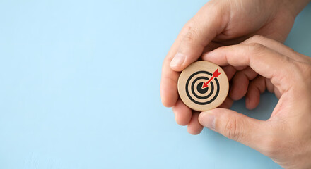 Hands holding wooden target with red dart on blue background