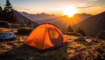 Orange Camping Tent Set Up On Grassy Hillside With Mountain Range Backdrop At Golden Hour Sunset With Sun Rays Shining Through Pine Trees