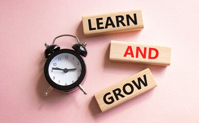 Learn and grow symbol. Concept words Learn and grow on wooden blocks. Beautiful pink background with alarm clock. Business and Learn and grow concept. Copy space.