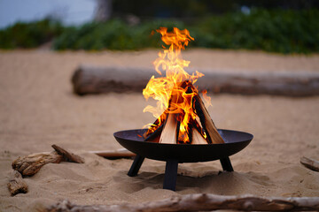 beach fire pit with burning wood on sand