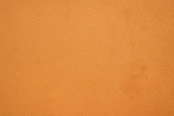 Vibrant orange stucco wall texture with cracks