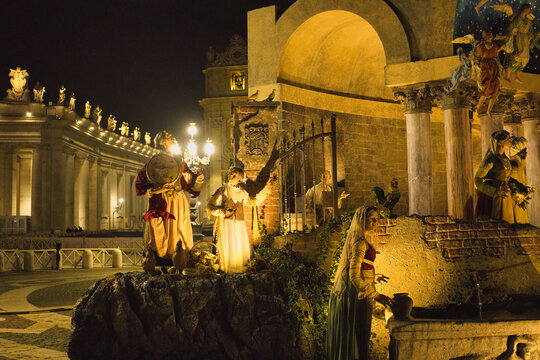 Roma , Italia , San Peter Square 12-18-2025. Nighttime Nativity Scene With Starry Arch, Festive Market Square, And Large Christmas Tree