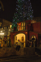 Roma , Italia , San Peter Square 12-18-2025. Nighttime Nativity Scene With Starry Arch, Festive Market Square, And Large Christmas Tree