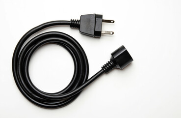 Black electric extension cord with plug and socket on white background. Coiled wire connects power for appliances. It is simple tool for electrical supply and energy transfer, ideal for various uses.