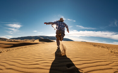 Happy young woman girl is having fun and runs at sunset desert dune against blue sky