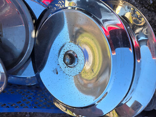 Metal wheel trims stacked on a blue cart