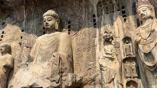Pan shot of statues of Vairocana Buddha modeled after Empress Wu Zetian, disciples and Bodhisattvas in Fengxian Temple Cave at Longmen Grottoes, Luoyang, Henan, China. UNESCO World Heritage Site.