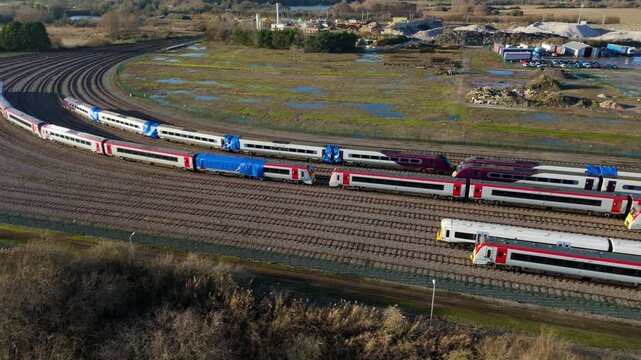 Aerial drone footage of large train yard depot, carriages and railway tracks, sunny afternoon in Ely, United Kingdom. 