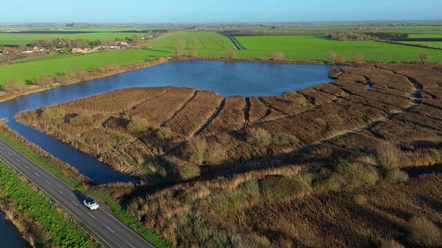 Aerial view of marshland and lake habitat, reed beds and blue water in fenland near Ely, United Kingdom. 