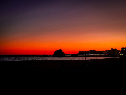 Stunning deep red sunset over the Mediterranean sea with the silhouette of Sa Palomera rock in Blanes, Spain.
