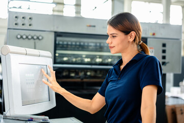 A professional female technician operating a modern industrial printing machine, touching a digital control panel screen in a factory. Precision manufacturing and automated technology concept.