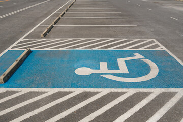 Accessible parking space with wheelchair symbol painted on the ground, showing disability access, inclusive public infrastructure, and barrier-free parking design in an outdoor parking lot.