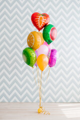 Fruit And Heart Balloons On Floor Against Zigzag Wall