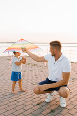 Father Playing With Son And Colorful Kite Outdoors