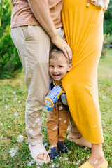 Expecting Parents With Playful Little Son In Garden