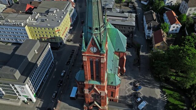 Top-down drone view of Trinity Church in Arendal city. Vertical aerial footage revealing the church roof, streets, and nearby city blocks in clear summer conditions.
