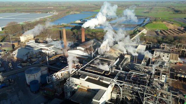Aerial drone footage of sugar production industry with chimneys silos and factory buildings near Wissington