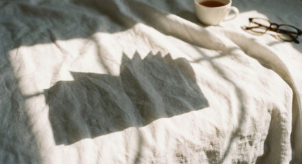 White linen background with open book and window shadow