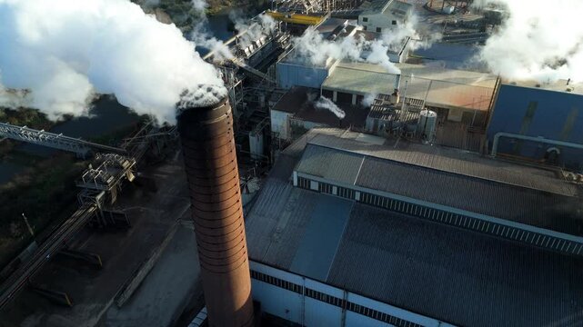 Close up aerial drone view of smoke stack chimney spewing smoke plumes at industrial factory site, sugar beet processing and production, Wissington, UK.