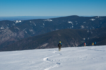 Skier standing on snowy mountain ridge overlooking vast winter landscape, wearing backpack and helmet, symbolizing adventure, freedom, backcountry skiing and alpine outdoor exploration