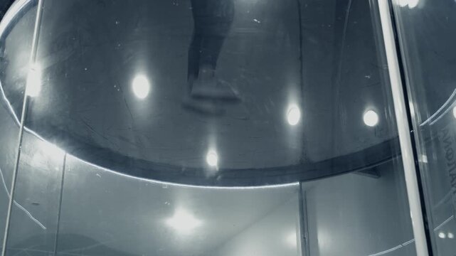 Professional male athlete flies up and down in a jumpsuit during an indoor skydiving training session in a vertical wind tunnel. Dynamic movement and skill mastery.