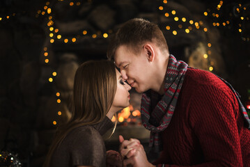 A young couple in love near the fireplace celebrates New Year and Christmas in a romantic atmosphere