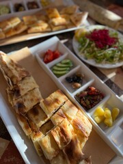 Traditional Turkish pide and salad served on a table with assorted side dishes