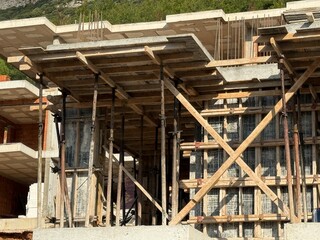 Construction site with scaffolding and wooden beams under an unfinished concrete building