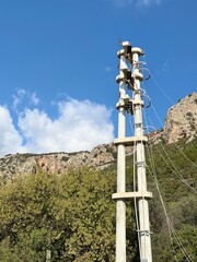 Power line against blue sky with rocky mountain background