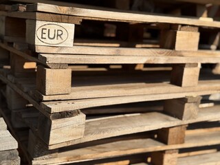 Wooden pallets stacked in sunlight, angled view with visible EUR mark, suitable for background