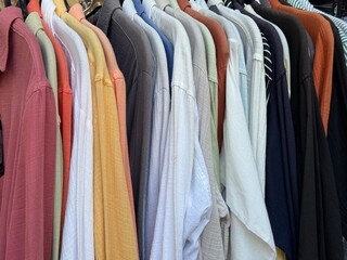 Rack of colorful shirts hanging closely together in a clothing store background
