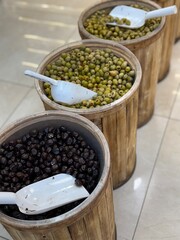 Barrels filled with assorted olives in a market setting with scoops on display