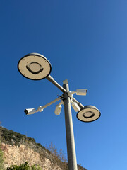 Street lights and security cameras against clear blue sky background