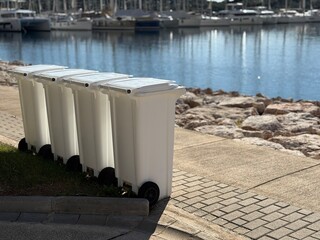 Trash bins lined up near waterfront marina, creating an interesting background concept