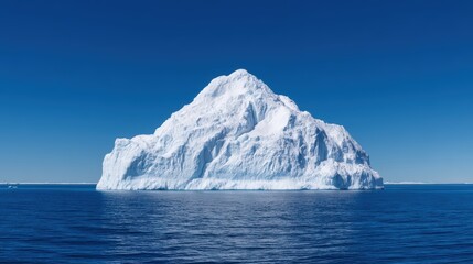 A majestic iceberg rises dramatically from the deep blue ocean, showcasing its towering, icy structure against a clear sky.