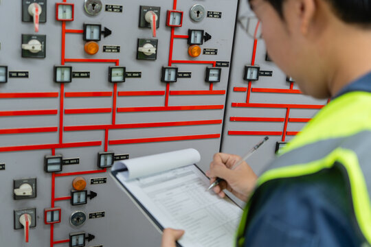 Electrical engineer auditing control panel data inside power facility, verifying operational records to ensure compliance, accuracy, and reliability for maintenance planning and stable electricity.