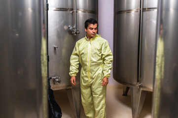 Expertise wine maker man working and inspecting wine from metal fermentation container in fermenting room