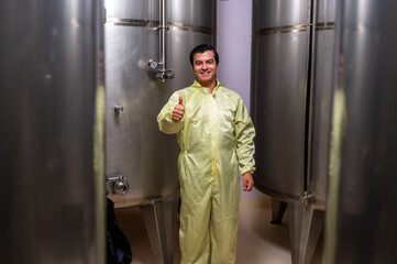 Expertise wine maker man working and inspecting wine from metal fermentation container in fermenting room