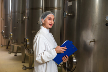 Expertise female wine maker working and inspecting wine in fermenting room 