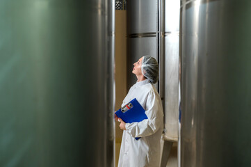 Expertise female wine maker working and inspecting wine in fermenting room 