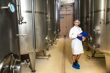 Expertise female wine maker working and inspecting wine in fermenting room 