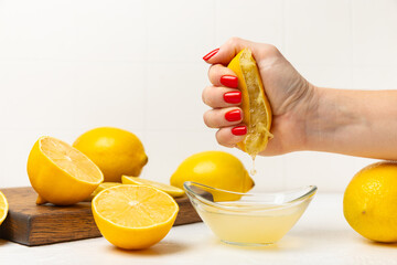 Lemon juice. Fresh lemon juice in a bowl. Ripe citrus, mint, fruit, and a juicer on the table. Vitamin C. Lemon water. Ingredient for baking or salad dressing. Space for text. Copy space.