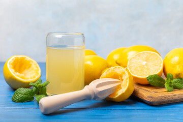 Lemon juice. Fresh lemon juice in a bowl. Ripe citrus, mint, fruit, and a juicer on the table. Vitamin C. Lemon water. Ingredient for baking or salad dressing. Space for text. Copy space.