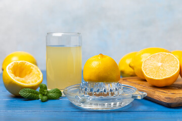 Lemon juice. Fresh lemon juice in a bowl. Ripe citrus, mint, fruit, and a juicer on the table. Vitamin C. Lemon water. Ingredient for baking or salad dressing. Space for text. Copy space.